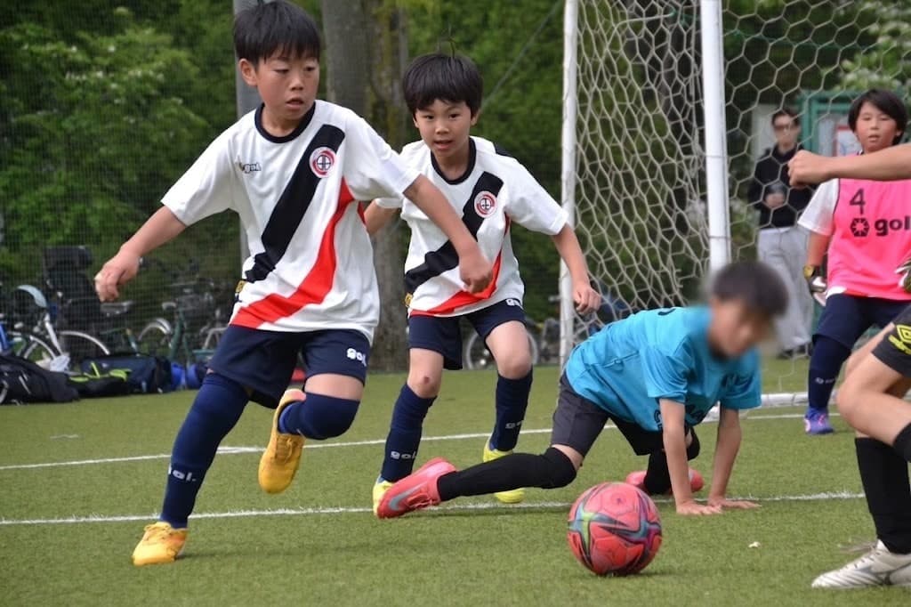 白黒赤のユニフォームでプレーする少年たち